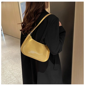 Modella che indossa una borsa baguette gialla lucida su un blazer nero in un corridoio