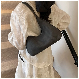 Detail of the woven texture and crescent shape on this minimalist black underarm bag