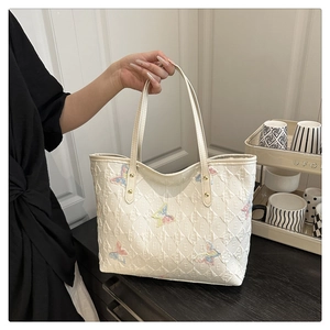 Détail du sac cabas blanc matelassé avec broderies papillon colorées et rivets dorés