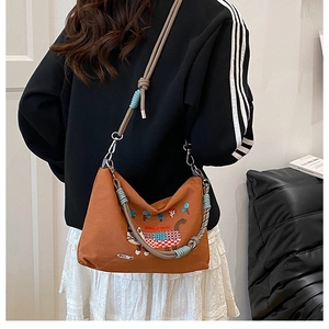 Close-up of caramel canvas tote bag with cat embroidery and woven handle detail