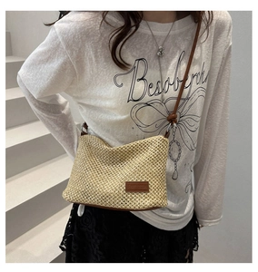 Détail d'un sac à bandoulière en paille tressée avec sangle en cuir brun et étiquette