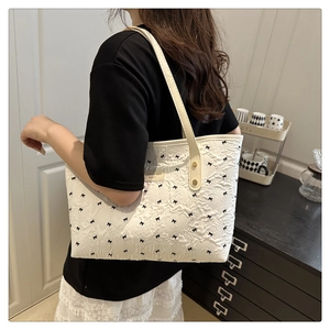Detailansicht der weißen Tote-Bag mit Schleifenmuster und Faltenstoff an einem Model