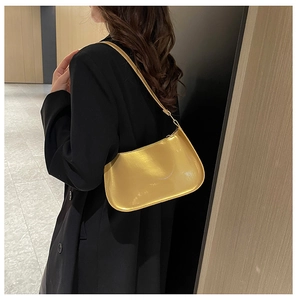 Vista laterale della borsa baguette dorata metallizzata su modella in un corridoio