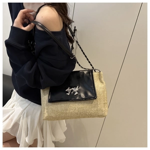 Detail of woven straw and black leather bag with silver bow buckle and chain strap