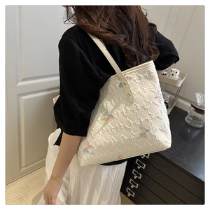 Détail de la broderie papillon sur sac cabas crème avec motif gaufré en relief E
