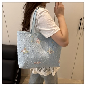 Detail of light blue tote bag featuring colorful sequined butterflies and embossed patterns