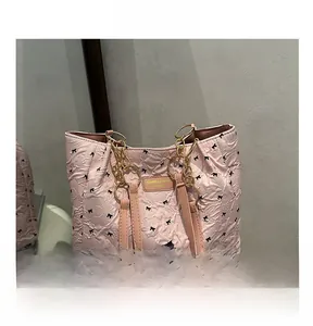 Detail of pink quilted tote bag with black bow print and gold chain shoulder strap