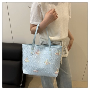Détail du cabas jacquard bleu clair avec monogramme 3D et papillons en sequins dégradés