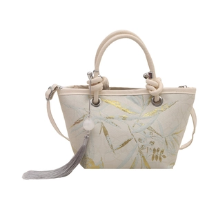 White canvas bucket bag with teal leaf print, cylindrical handles and grey silk tassel