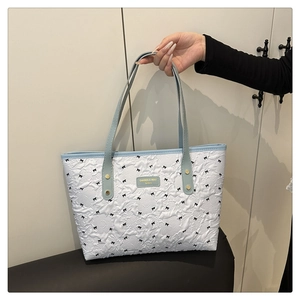 Detailansicht der weißen Prägetextur mit schwarzen Schleifen und hellblauem Griff der Tasche