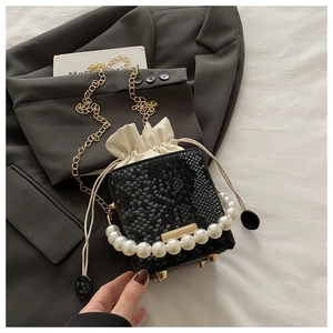 Detail of black snake pattern bucket bag with pearl handle and golden chain strap