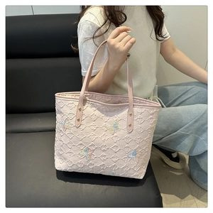 Détail du sac cabas rose montrant la texture gaufrée et les papillons brodés