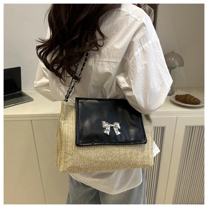 Detail of straw and leather crossbody bag featuring a silver bow buckle and chain strap