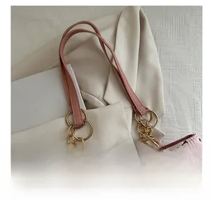 Detail of pink tote bag with black bow pattern and golden metal chain handle