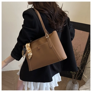 Close-up of brown PU leather tote bag featuring white stitching and silk scarf detail