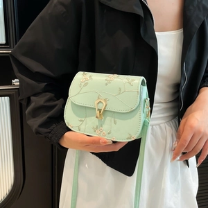 Sacoche vert menthe avec broderie florale et boucle fer à cheval dorée sur modèle
