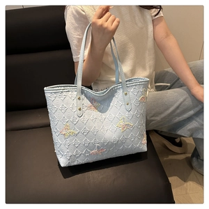 Détail du sac cabas bleu clair avec appliques papillon colorées et texture matelassée