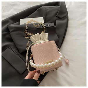 Detailed macro view of pink snakeskin pattern bucket bag with pearl handle and chain
