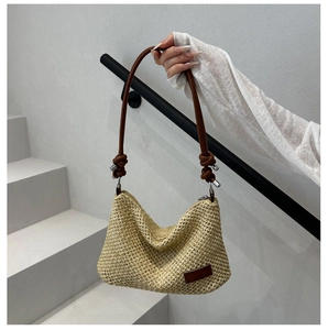 Vue détaillée du sac cabas en paille tissée avec bandoulière en cuir brun et anneau métal