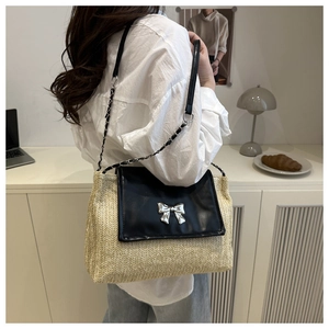 Detail of straw woven texture and black leather flap with silver bow metal buckle