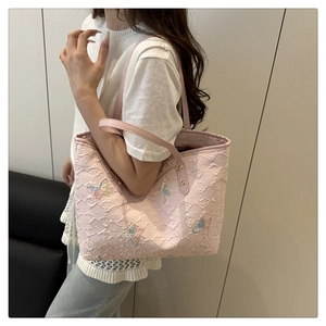 Close-up of pink embossed floral tote with colorful butterfly embroidery details
