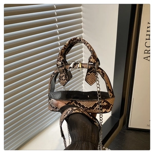 Detail der Schlangenhaut-Textur und transparentem PVC an der Muscheltasche mit Kette