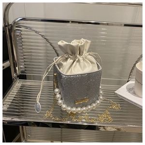 Detail of silver python texture bucket bag with pearl handle and golden chain