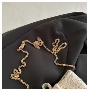 Close-up of golden metal chain strap on a woven bucket bag with romantic engraving