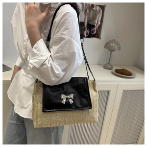Detail of a straw woven shoulder bag with a black leather flap and silver bow buckle