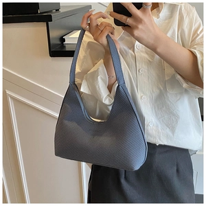 Detail of grey-blue shoulder bag featuring woven texture and curved zipper closure