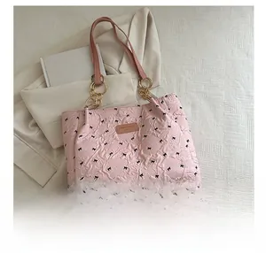 Macro shot of pink quilted tote bag with black bow patterns and gold chain link detail