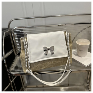 Detail of straw woven texture with white leather flap and silver bow buckle on the bag