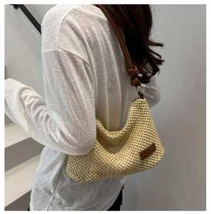 Détail du sac en paille tressé avec écusson logo en cuir et bandoulière à nœud élégant