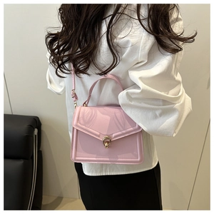 Model view of pink patent leather handbag with gold twist lock and crossbody strap