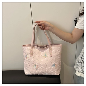 Détail du sac cabas rose avec gaufrage floral et broderies de papillons colorés