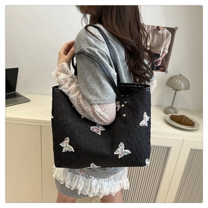 Detail of 3D butterfly embroidery and embossed pattern on black tote shoulder bag