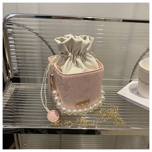 Detail of light pink snake skin textured bucket bag with pearl handle and gold chain
