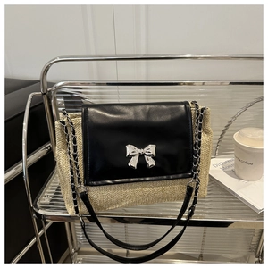 Close-up of the woven straw texture and silver bow buckle on the black leather flap