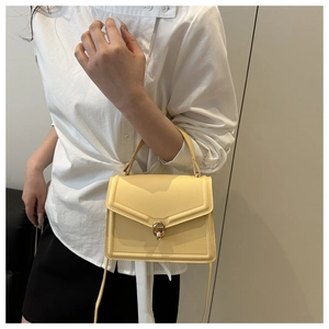 Detail of light yellow leather crossbody bag with triangular flap and gold hardware