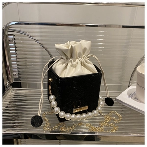 Detail of black snake pattern bucket bag with pearl handle and golden chain strap