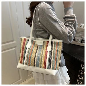 Gros plan sur un sac cabas en paille à rayures colorées avec des anses en cuir blanc