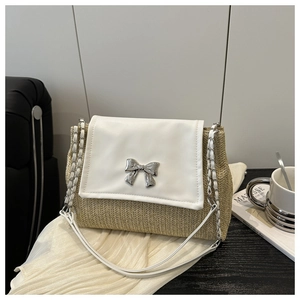 Close-up of beige woven straw bag with white leather flap and silver bow detail