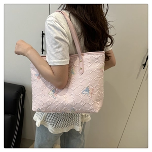 Détail du sac cabas rose matelassé avec broderie papillon colorée et rivets dorés