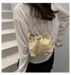 Detail of beige woven bucket bag with floral embroidery and pearl drawstring accents