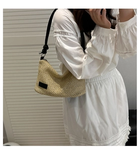 Détail du sac à bandoulière en paille tressée avec bandoulière en cuir noir nouée
