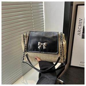 Detail of straw and black leather crossbody bag featuring a silver bow metal buckle