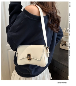 Close-up of a white leather shoulder bag with a vintage gold twist lock and curved base