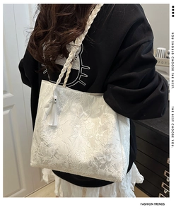 Detail of white lace tote bag with floral butterfly embroidery and decorative tassel