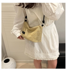 Détail du sac bandoulière en paille beige tissé main avec cordon noir et étiquette latérale