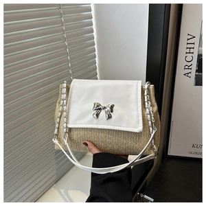 Detail of straw woven texture and silver bow buckle on the elegant white flap bag